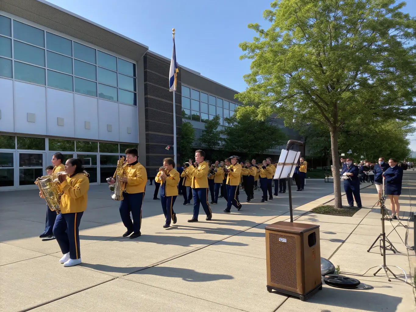 A group of BFAD students enthusiastically playing brass instruments during an outdoor performance, showcasing their skill and teamwork.